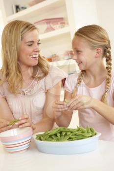 Young woman with child splitting pea in kitchen