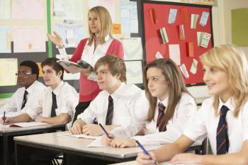 Teenage Students Studying In Classroom With Teacher