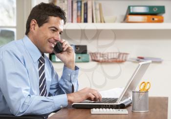 Man Working From Home Using Laptop On Phone