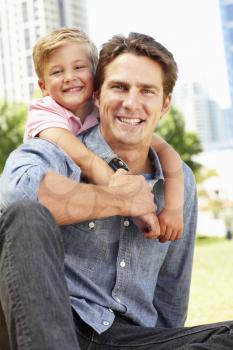 Man sitting in city park with young son