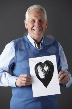 Senior man holding ink drawing of heart