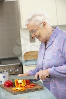 Senior woman chopping vegetables in domestic kitchen