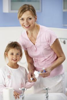 Mother and daughter cleaning teeth in bathroom