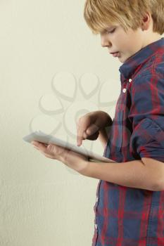 Studio Shot Of Young Boy Holding Tablet Computer