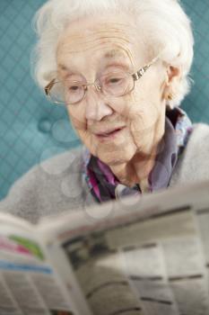 Senior Woman Relaxing In Chair Reading Newspaper