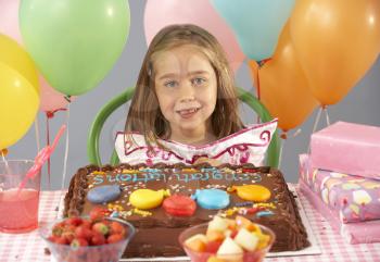 Young girl with birthday cake and gifts at party