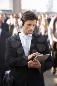 Male commuter in crowd with tablet and headphones