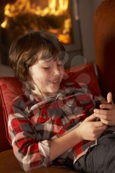 Young Boy Relaxing With MP3 Player By Cosy Log Fire