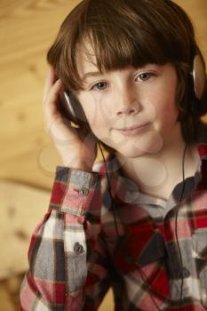 Young Boy Sitting On Wooden Seat Listening To MP3 Player