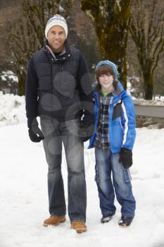 Father And Son Walking Along Snowy Street In Ski Resort