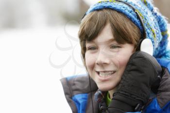 Boy Wearing Headphones And Listening To Music Wearing Winter Clothes In Snowy Landscape
