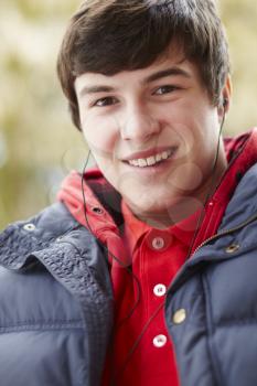 Teenage Boy Wearing Earphones And Listening To Music Wearing Winter Clothes