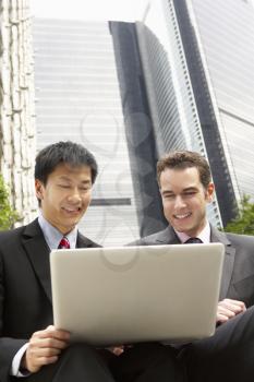 Portrait Of Two Businessmen Working On Laptop Outside Office