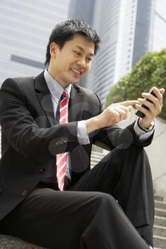 Chinese Businessman Dialling On Mobile Phone Outside Office