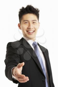 Studio Portrait Of Chinese Businessman Reaching Out To Shake Hands