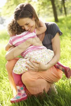 Mother Cuddling Young Daughter In Summer Field