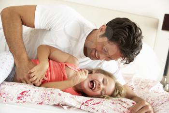 Father And Daughter Relaxing Together In Bed