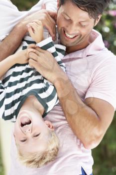 Father Holding Son Upside Down Outdoors