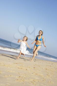 Mother And Daughter Running Along Beach