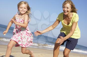 Grandmother And Granddaughter Running Along Beach
