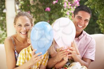 Family Sitting On Sofa Together With Balloons