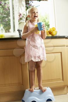 Girl Standing On Plastic Step In Kitchen Helping With Washing Up