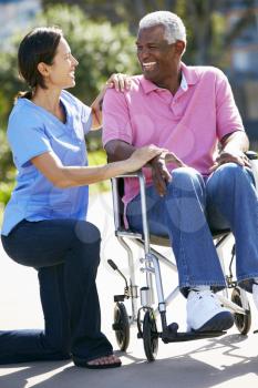 Carer Pushing Senior Man In Wheelchair