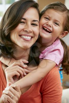 Portrait Of Mother And Daughter Sitting On Sofa At Home