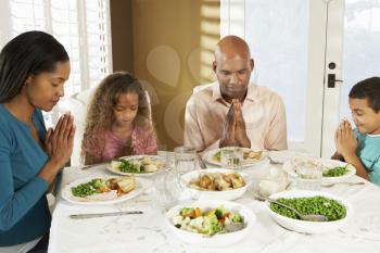 Family Saying Grace Before Meal At Home