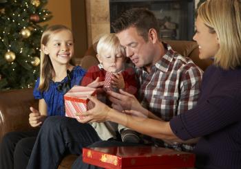 Family Opening Presents In Front Of Christmas Tree