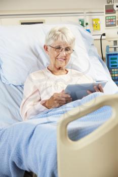 Senior Female Patient Relaxing In Hospital Bed With Digital Tablet