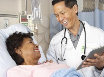 Doctor Using Digital Tablet Talking With Senior Patient