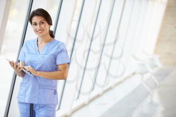 Nurse Using Digital Tablet In Corridor Of Modern Hospital