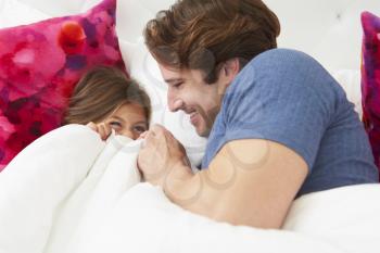 Father And Daughter Lying In Bed Together