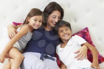 Mother And Children Relaxing In Bed Wearing Pajamas