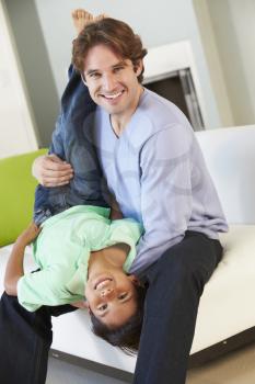 Father And Son Having Fun On Sofa Together