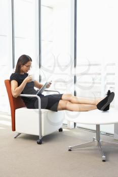 Businesswoman Relaxing With Digital Tablet During Break