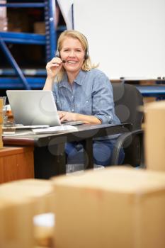 Worker In Warehouse Wearing Headset And Using Laptop