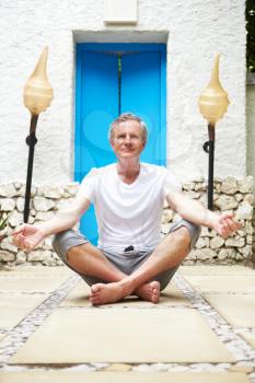 Senior Man Meditating Outdoors At Health Spa