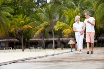 Senior Couple Walking On Wooden Jetty