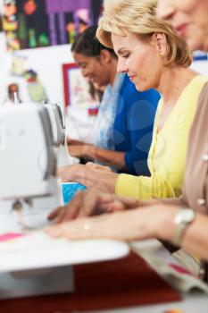 Group Of Women Using Electric Sewing Machines In class