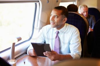 Businessman Commuting On Train Using Digital Tablet