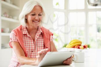 Middle Aged Woman Using Digital Tablet Over Breakfast