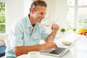 Middle Aged Man Using Laptop Over Breakfast