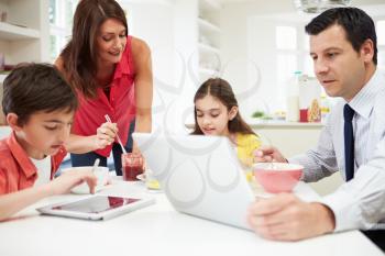 Family Using Digital Devices At Breakfast Table