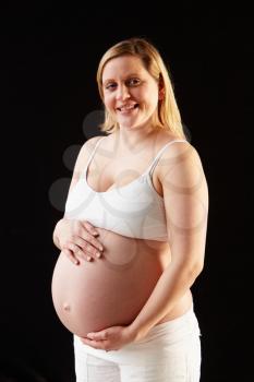 Portrait Of Pregnant Woman Wearing White On Black Background