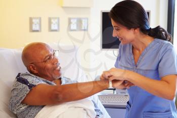 Nurse Putting Wristband On Senior Male Patient In Hospital