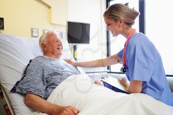 Nurse Talking To Senior Male Patient In Hospital Room