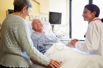 Female Doctor Talking To Senior Couple In Hospital Room