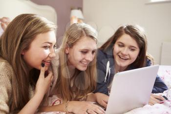 Three Teenage Girls Using Laptop In Bedroom